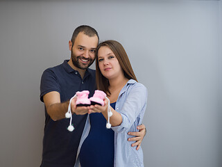 Image showing pregnant couple holding newborn baby shoes