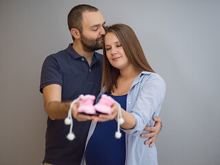 Image showing pregnant couple holding newborn baby shoes