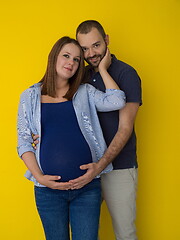 Image showing pregnant couple  isolated over yellow background