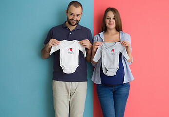 Image showing young couple holding baby bodysuits