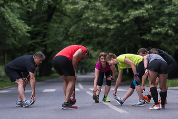 Image showing runners team warming up and stretching before morning training