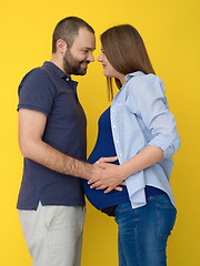 Image showing pregnant couple  isolated over yellow background