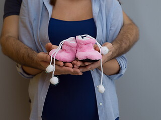 Image showing pregnant couple holding newborn baby shoes