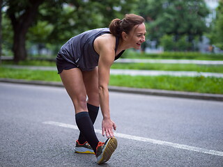 Image showing female runner warming up and stretching before morning training