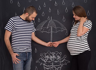 Image showing pregnant couple drawing their imaginations on chalk board