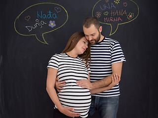 Image showing pregnant couple posing against black chalk drawing board