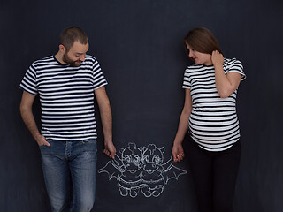 Image showing pregnant couple drawing their imaginations on chalk board