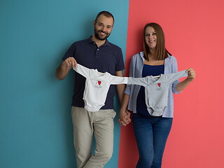 Image showing young couple holding baby bodysuits