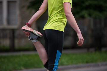 Image showing female runner warming up and stretching before morning training