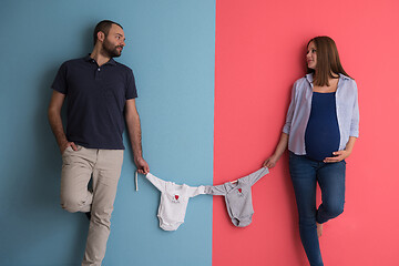 Image showing young couple holding baby bodysuits