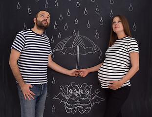 Image showing pregnant couple drawing their imaginations on chalk board