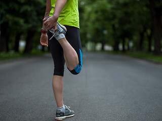 Image showing female runner warming up and stretching before morning training