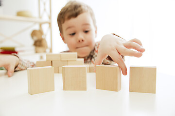 Image showing Little child sitting on the floor. Pretty boy palying with wooden cubes at home