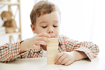 Image showing Little child sitting on the floor. Pretty boy palying with wooden cubes at home