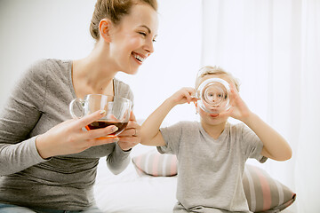 Image showing Young mother and her little daughter hugging and kissing on bed