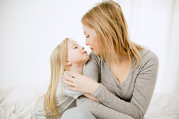 Image showing Young mother and her little daughter hugging and kissing on bed