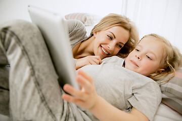 Image showing Young mother and her little daughter hugging and kissing on bed