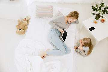 Image showing Young mother and her little daughter hugging and kissing on bed