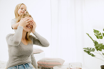 Image showing Young mother and her little daughter hugging and kissing on bed