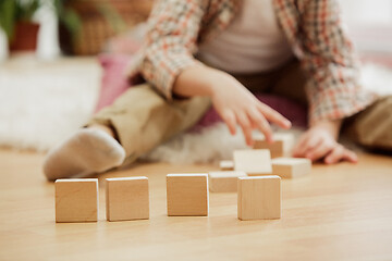 Image showing Little child sitting on the floor. Pretty boy palying with wooden cubes at home