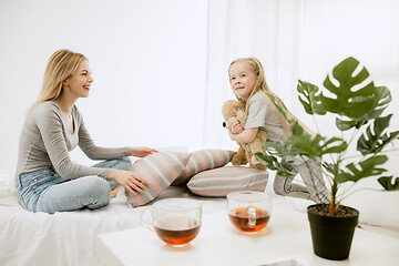 Image showing Young mother and her little daughter hugging and kissing on bed