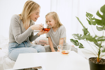 Image showing Young mother and her little daughter hugging and kissing on bed