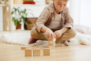 Image showing Little child sitting on the floor. Pretty boy palying with wooden cubes at home