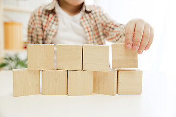 Image showing Little child sitting on the floor. Pretty boy palying with wooden cubes at home