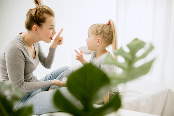 Image showing Young mother and her little daughter hugging and kissing on bed