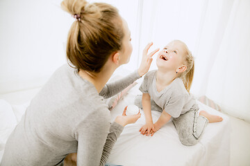 Image showing Young mother and her little daughter hugging and kissing on bed