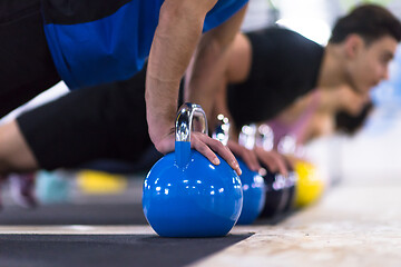 Image showing young athletes doing pushups with kettlebells