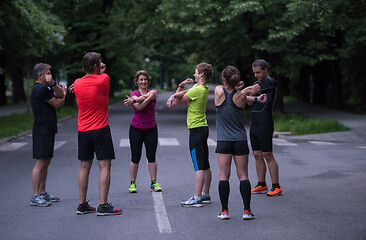 Image showing runners team warming up and stretching before morning training