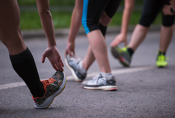 Image showing runners team warming up and stretching before morning training