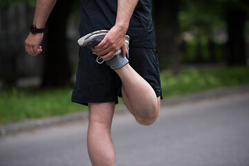 Image showing male runner warming up and stretching before morning training