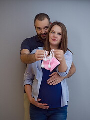 Image showing pregnant couple holding newborn baby shoes