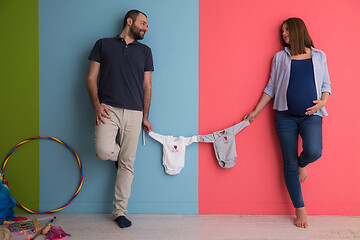 Image showing young couple holding baby bodysuits