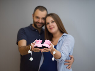 Image showing pregnant couple holding newborn baby shoes