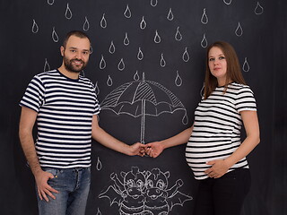 Image showing pregnant couple drawing their imaginations on chalk board