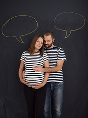 Image showing pregnant couple posing against black chalk drawing board