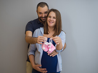 Image showing pregnant couple holding newborn baby shoes