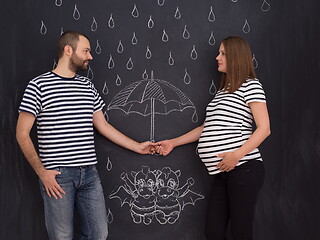 Image showing pregnant couple drawing their imaginations on chalk board