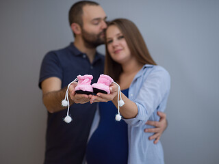 Image showing pregnant couple holding newborn baby shoes