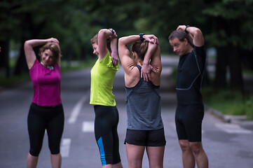 Image showing runners team warming up and stretching before morning training