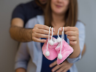 Image showing pregnant couple holding newborn baby shoes