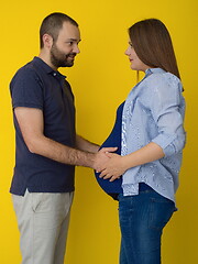 Image showing pregnant couple  isolated over yellow background