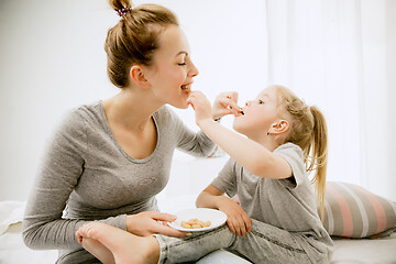 Image showing Young mother and her little daughter hugging and kissing on bed