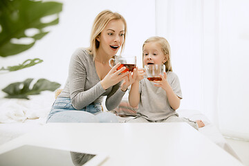 Image showing Young mother and her little daughter hugging and kissing on bed