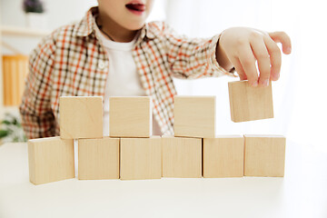 Image showing Little child sitting on the floor. Pretty boy palying with wooden cubes at home