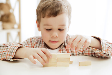 Image showing Little child sitting on the floor. Pretty boy palying with wooden cubes at home