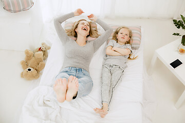 Image showing Young mother and her little daughter hugging and kissing on bed